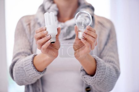 Photo for Woman, closeup and hands with different lightbulb in house for choice, comparison or balance. Energy, electricity or female person with globe decision for power efficiency, saving or sustainability. - Royalty Free Image