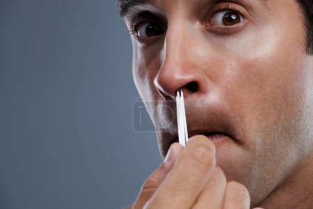 Photo for Man, nose and hair with tweezers in studio on grey background for self care, wellness or dermatology. Male person, face and grooming for cosmetic beauty or healthy cleaning, wellbeing or mockup space. - Royalty Free Image