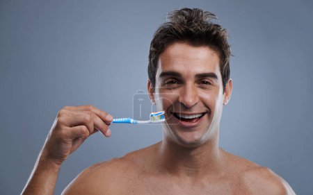 Photo for Portrait, man or wellness with toothbrush, oral hygiene or body care on grey studio background. Face, person or model with fresh breath or health with toothpaste or morning routine with dental smile. - Royalty Free Image