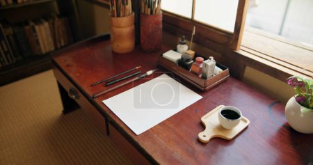 Foto de Tinta, pincel y arte japonés con papel sobre un escritorio en un estudio casero con herramientas de creatividad. Papel creativo, pintor y artista con documento de boceto y caligrafía con lápiz y dibujo. - Imagen libre de derechos