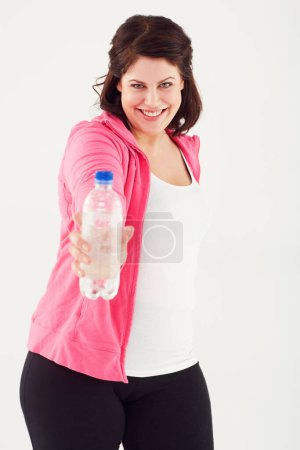 Téléchargez les photos : Femme heureuse, portrait et taille plus avec bouteille d'eau en forme pour une nutrition naturelle sur fond de studio blanc. Visage de la femme sourire avec une boisson minérale pour la durabilité ou l'hydratation. - en image libre de droit