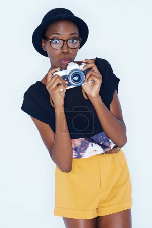 Foto de Mujer, sorprendida y fotógrafa en retrato en estudio, creatividad y talento para artista en trabajo creativo. Persona africana, diseño o cara en sesión de fotos por cámara o sorpresa por lente sobre fondo blanco. - Imagen libre de derechos