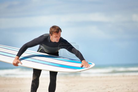 Téléchargez les photos : Surf, plage et homme avec planche de surf par l'océan pour l'entraînement de sports nautiques, l'exercice et la remise en forme à l'extérieur. Nature, Voyage et personne vérifier l'équipement pour l'aventure en vacances, vacances et passe-temps par la mer. - en image libre de droit