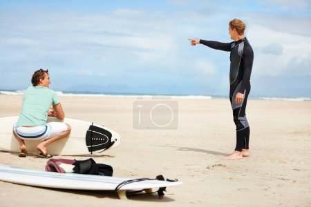 Téléchargez les photos : Surf, plage et hommes pointant avec planche de surf pour les sports nautiques, fitness et exercice par l'océan. Nature, amis et personnes avec geste de la main pour la direction en vacances, vacances et aventure par la mer. - en image libre de droit