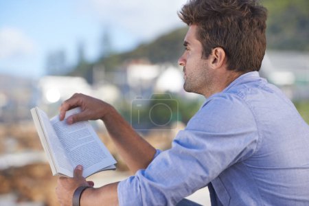 Photo for Nature, story and young man reading for knowledge, fun or relaxing hobby on vacation or holiday. Travel, outdoor and handsome confident male person enjoying book or novel on weekend trip or adventure. - Royalty Free Image