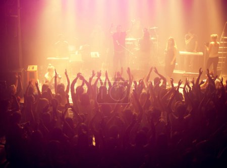 Téléchargez les photos : Concert, public et musique rock avec les mains en l'air de personnes au DJ, groupe et festival événement sur une scène avec des lumières. Spectacle, danse et fête avec foule excitée en rave, techno et divertissement sur place. - en image libre de droit