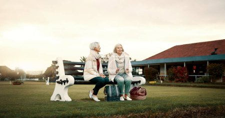 Photo for Talking, senior friends and at a club for sports, fitness break and sitting together after exercise. Happy, relax and elderly women on a field bench for conversation, retirement hobby or activity. - Royalty Free Image