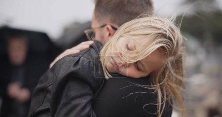 Photo for Sad, death and a daughter with her father at a funeral for grief or mourning loss together outdoor. Family, empathy and a man holding his girl child at a memorial service or ceremony for condolences. - Royalty Free Image