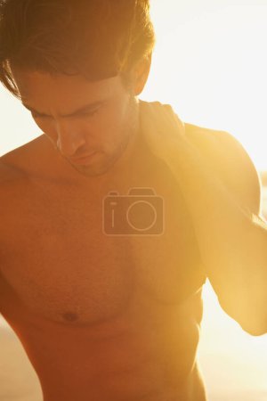 Photo for Man, shirtless and travel to beach at sunset, confidence and tourist at sea on summer holiday. Male person, topless and outdoor adventure for fun, calm ocean and peaceful environment in nature. - Royalty Free Image
