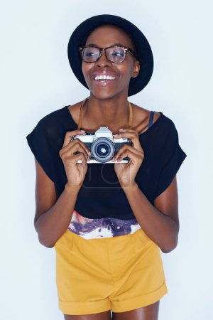 Téléchargez les photos : Femme noire, photographe et bonheur en studio avec caméra, créativité et talent dans les médias dans la carrière d'artiste. Jeune, positif et vision pour photoshoot et lentille de mise au point par fond blanc. - en image libre de droit