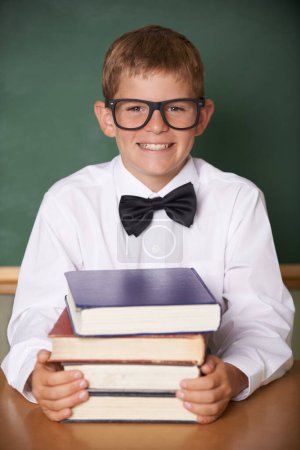 Photo for Boy child, smile and portrait with books, classroom and learning for exam, assessment and studying for knowledge. Student kid, notebook and happy for education, development and glasses at table. - Royalty Free Image
