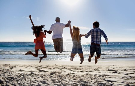 Téléchargez les photos : Sauter, plage et dos d'amis se tenant la main en vacances ensemble en été en mer. Groupe, hommes heureux ou excités avec des femmes dans la célébration amusante de la liberté par l'océan, le sable, la nature pour les voyages. - en image libre de droit