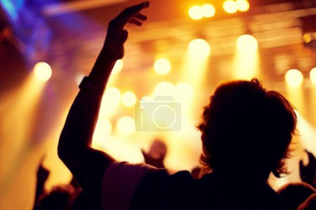 Photo for Night, club and man dance at concert, event or music festival with stage lights and silhouette. Dark, nightclub and person in audience, crowd and social celebration at techno rave with energy. - Royalty Free Image