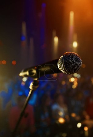 Photo for Microphone, closeup and stage performance in theater with sound equipment for concert or singing. Audio, technology and light in dark room with audience for karaoke, music or event for culture. - Royalty Free Image