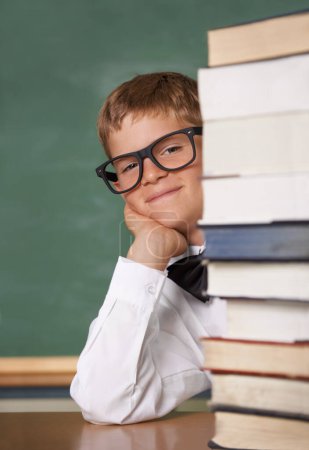 Photo for Child, school portrait and stack of books for education, language learning and knowledge in classroom. Happy face of kid, boy or student in glasses with textbook, literature and library resources. - Royalty Free Image