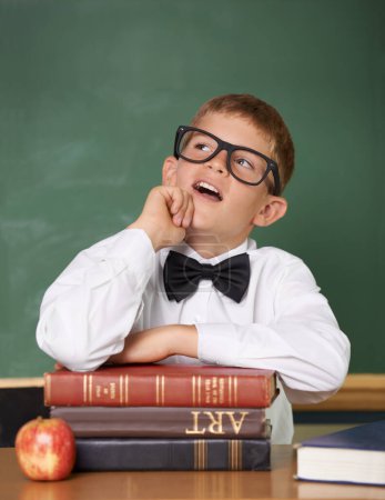 Photo for Boy child, books and classroom with thinking, ideas or information for knowledge, solution and school. Student, problem solving and brainstorming for education, learning or development with glasses. - Royalty Free Image