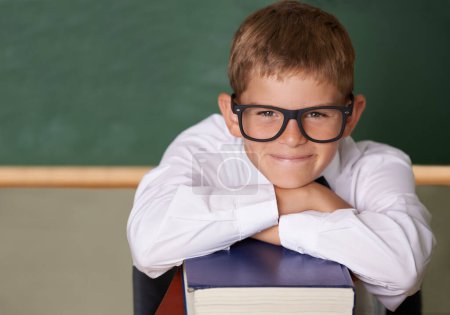 Photo for Happy boy, portrait and relax on books at school for learning, education or knowledge with green chalk board. Face of male person, smart child or young teenager smile for academic literature in class. - Royalty Free Image