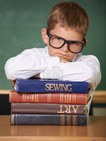 Photo for Frustrated boy child, books and portrait in classroom for knowledge, information and studying at academy. Student kid, learning and education with glasses, angry and stress for assessment at school. - Royalty Free Image