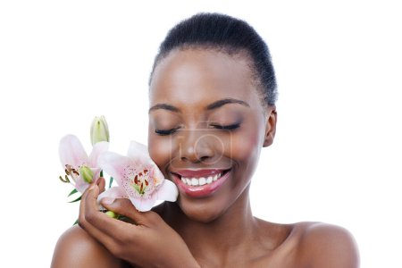 Photo for Black woman, flower and smile for natural beauty, dermatology and skincare for glow and wellness on white background. Nature, skin and sustainable cosmetics, face with shine and orchid in a studio. - Royalty Free Image