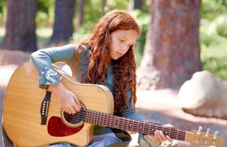 Photo for Nature, camp and girl child with guitar for entertainment, talent or music in woods or forest. Playing, musician and kid with acoustic string instrument outdoor in park or field on weekend trip - Royalty Free Image