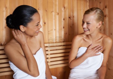 Foto de Mujeres, relajarse y hablar en la sauna en el spa con desintoxicación saludable de sudor para la belleza, el bienestar y el cuidado de la piel. Amigos, tratamiento y sentarse en la sala de vapor con una sonrisa para anti-envejecimiento beneficios para el cuerpo. - Imagen libre de derechos