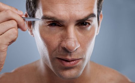 Photo for Man, portrait and tweezers for eyebrows or grooming for face clean, hygiene or grey background. Male person, pluck and hair removal for healthy morning routine or studio, treatment or mockup space. - Royalty Free Image
