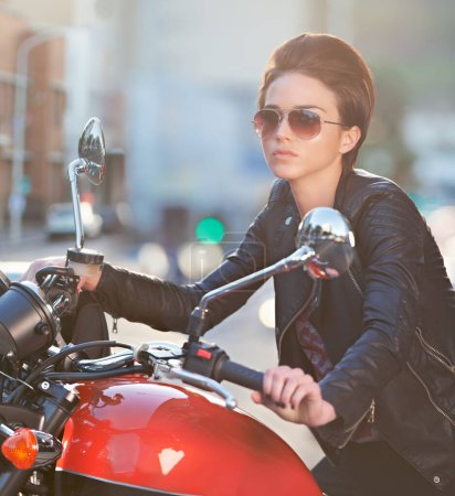 Photo for Motorcycle, power and woman in city with sunglasses for travel, transport or road trip as rebel. Fashion, street and model in leather jacket on classic or vintage bike for transportation or journey. - Royalty Free Image