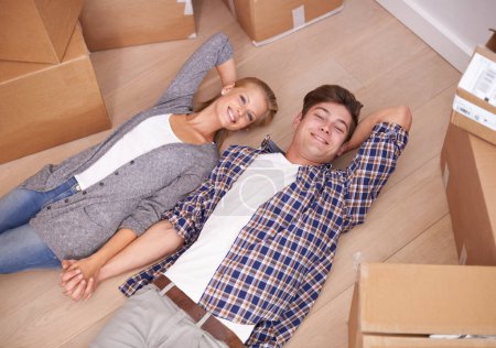 Photo for Man, woman and portrait and floor with moving boxes or relax or real estate investing as new beginning, relocation or marriage. Couple, happy and rest bonding in apartment or rent, above or packing. - Royalty Free Image