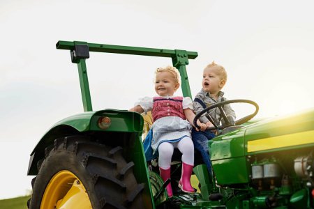 Foto de La próxima generación de agricultores. Disparo de dos niños adorables montando un tractor juntos en una granja - Imagen libre de derechos