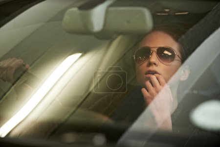 Photo for Woman, driving and mirror to reverse from parking garage for journey or trip with sunglasses. Face, female person and car window to think on roadtrip in vehicle for commute with stylish eyewear. - Royalty Free Image