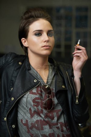 Foto de Fumar, estilo y moda cool de una mujer pensando con un cigarrillo en la mano. Punk, ropa atrevida y joven mujer con tabaco por un hábito poco saludable con nicotina de moda y confianza. - Imagen libre de derechos