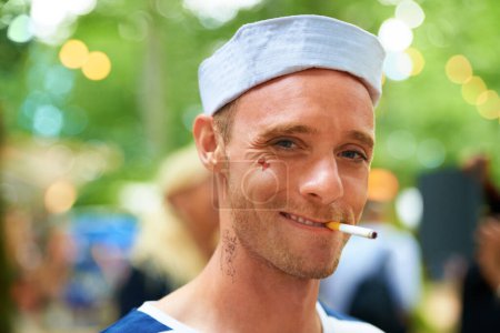 Photo for Portrait, smile and man with a cigarette, music festival and sailor outfit with fun and costume. Face, person and guy with tobacco, outdoor or nicotine with concert or happy with culture or bad habit. - Royalty Free Image