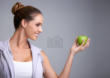 Photo for Happy, health and woman in studio with apple, offer or mockup for fiber or gut health on grey background. Nutrition, space and model with fruit for weight loss help, nutrition or raw superfoods diet. - Royalty Free Image