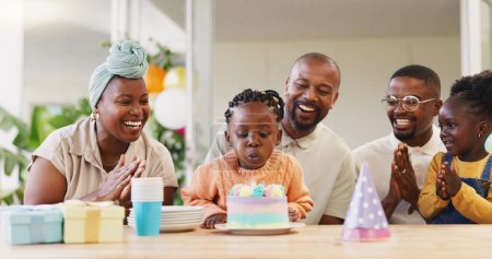 Photo for Birthday, kids party and applause with a black family in celebration of a girl child in their home. Parents, grandparents and children clapping while blowing candles on a cake at a milestone event. - Royalty Free Image
