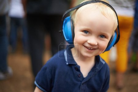 Photo for Portrait, child and noise cancelling headphones at outdoor event with smile, fun and music. Protection, happiness and boy toddler at festival, concert or live performance with soundproof headset - Royalty Free Image