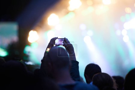 Téléchargez les photos : Mains, téléphone portable et photographie lors d'un concert de musique dans la foule pour les médias sociaux post pour les vacances, carnaval ou la nuit. Silhouette, photo et événement d'été ou fête de voyage ou sombre extérieur, lumières ou festival. - en image libre de droit