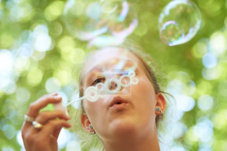 Photo for Woman, bubbles and blowing outdoor for fun on weekend, break or holiday for relax and summer entertainment. Person, closeup and plastic wand or toy for playing and leisure on vacation or adventure. - Royalty Free Image