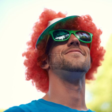 Photo for Man, wig and sunglasses with nature, sky and festival for fun, joy and celebration. Person, summer and concert with low angle, smile and happy for event, party or sunshine for celebration and closeup. - Royalty Free Image