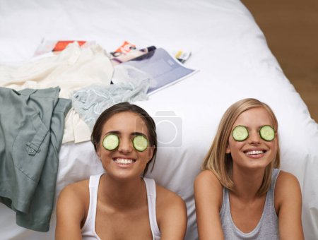Photo for Women, spa and friends in bedroom, smile and self care on bed together. Sisters, cucumber and wellness connect for home, relaxation and beauty talk for happiness, skincare and antioxidant treatment. - Royalty Free Image