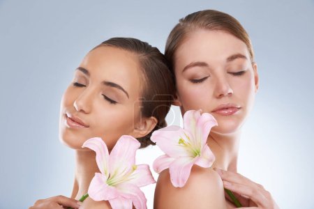 Photo for Woman, relax and skincare with flowers for natural beauty, makeup or cosmetics on a blue studio background. Young female, people or models smile in satisfaction for spa, soft skin or facial treatment. - Royalty Free Image