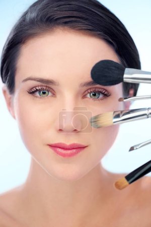 Photo for Woman, portrait and makeup brushes in studio with skincare, cosmetic tools or product application for beauty. Model, face and confidence with skin wellness, cosmetology or grooming on blue background. - Royalty Free Image