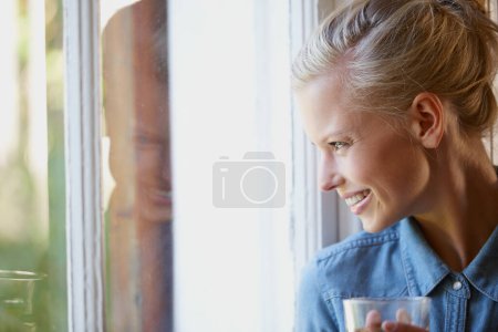 Thinking, smile and woman with coffee in a house for peaceful, reflection or moment at home. Remember, face and female person with happy memory, tea or enjoying me time or weekend at apartment window.