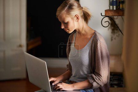 Photo for Woman, freelancer and laptop for networking, remote work and internet connection in kitchen for info. Female person, editor and website for research or online news, blog and typing an article on tech. - Royalty Free Image