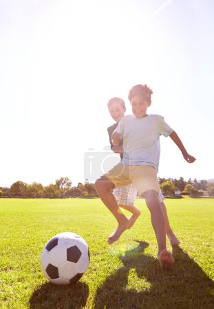 Téléchargez les photos : Football, amis et jouer pour le plaisir sur l'herbe, le soutien et le sourire pour le jeu de sport sur le terrain. Garçons heureux, les enfants et la performance sur le terrain extérieur, coller et rire pour la compétition ou défi. - en image libre de droit