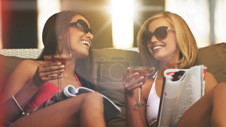 Photo for Friends, women and happy with alcohol at hotel, bonding and drinking wine on tropical vacation. People, reading news and magazine for gossip on summer holiday, weekend trip and travel to resort. - Royalty Free Image