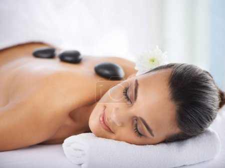 Photo for Calm, hot stone and woman with massage at spa for wellness, health and back treatment. Self care, cosmetic and young female person sleeping for warm stone back therapy at natural beauty salon - Royalty Free Image