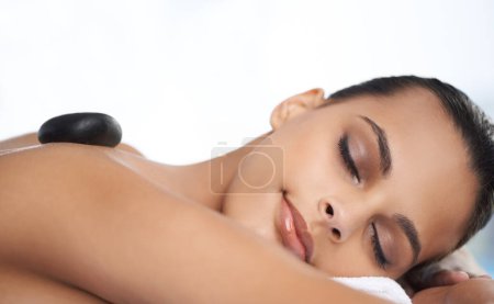 Téléchargez les photos : Détendez-vous, pierre chaude et femme avec massage au spa pour le bien-être, la santé et le traitement du dos. Auto-soin, cosmétique et jeune femme dormant pour une thérapie de dos en pierre chaude au salon de beauté naturel - en image libre de droit
