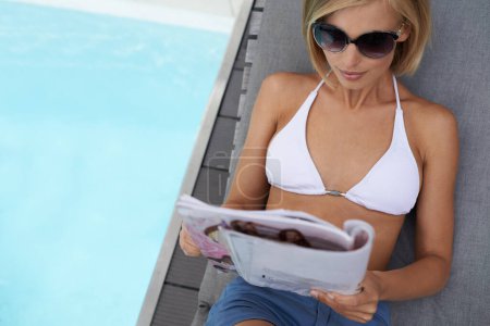 Photo for Relax, woman and reading a magazine by pool on chair in summer, vacation and travel on holiday. Bikini, person and journal outdoor at deck for leisure, top view and mockup space on water at hotel. - Royalty Free Image