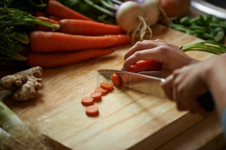 Téléchargez les photos : Légumes, mains et personne avec couteau et carotte coupés et pour cuisiner le déjeuner et l'alimentation à la maison. Bien-être, santé et alimentation biologique avec repas, végétarien et ingrédients pour salade dans une cuisine. - en image libre de droit