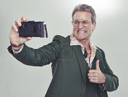 Foto de Hombre mayor, moda y selfie con pulgares hacia arriba para un buen trabajo, ganar o fotografía en un fondo de estudio gris. Persona madura en estilo retro o vintage y como emoji o sí signo de foto o imagen. - Imagen libre de derechos